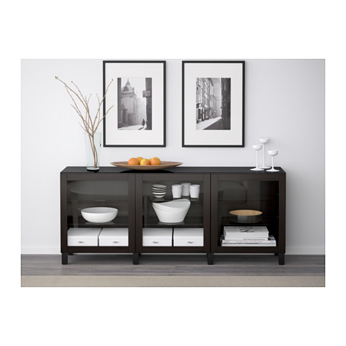 Moderno aparador negro con puertas de vidrio, que muestra platos blancos y fotos arriba.