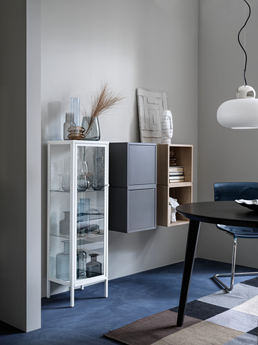 Sala de estar moderna con gabinete blanco, artículos de vidrio, jarrones, arte, mesa negra y lámpara colgante.