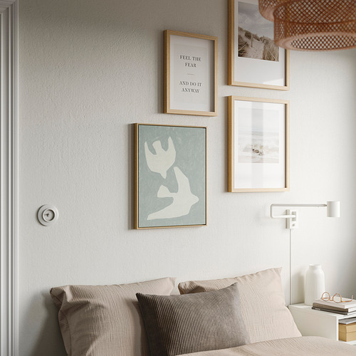 Acogedor dormitorio con marco BLODFLÄDER sobre la cama, que añade elegancia.