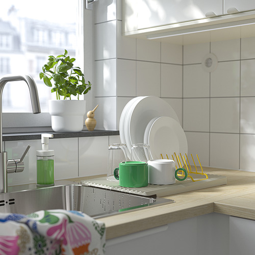Fregadero de cocina moderno con dispensador de jabón verde, portaplatos amarillo-verde y grifo de acero inoxidable.