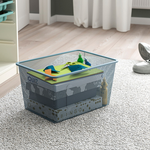 Caja de almacenamiento de malla en el suelo, con artículos coloridos, diseñada para un fácil acceso y organización.
