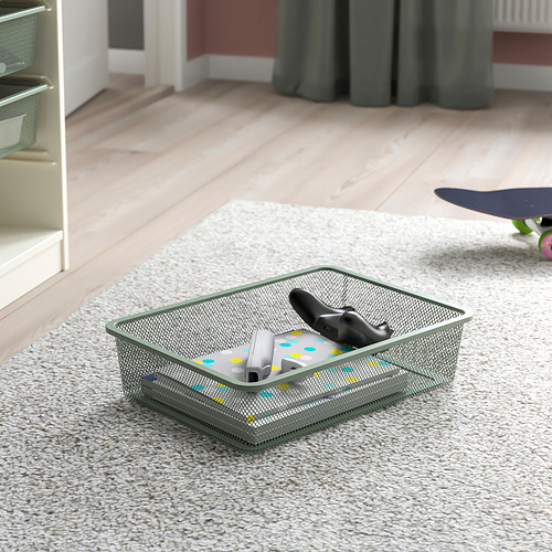 La caja de almacenamiento de malla en el piso alfombrado contiene accesorios de juego, adecuada para organizar artículos en el interior.