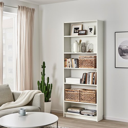 Moderno salón con cesta TÄTING en estantería billy, además de sofá gris y ventana con cortinas.