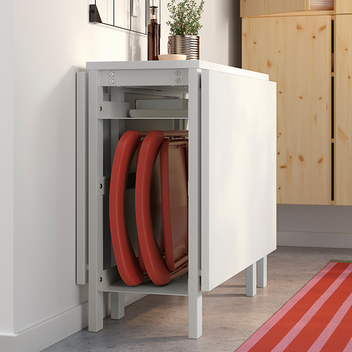 Armario abierto para almacenar sillas apilables rojas. Tapa de armario de madera con planta y botella. Habitación luminosa y minimalista.