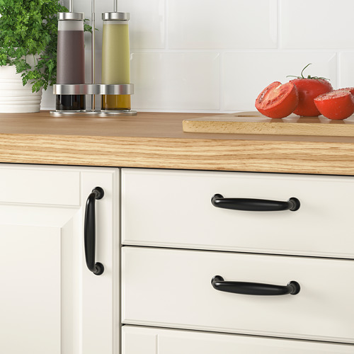 Encimeras de cocina modernas con encimera de madera, armarios blancos, manijas negras, tomates en rodajas, hierbas y dispensadores de aceite.