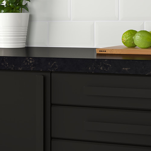 Encimera de cocina negra con gabinetes oscuros, tazas blancas, frutas de lima y una pequeña planta en maceta. Adecuado para puertas de 16-21 mm de grosor.