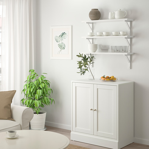 Salón minimalista con estantería TREHULT, platos, jarrón, plantas y frutas.