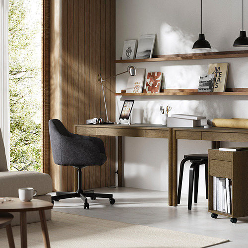Moderna oficina en casa con escritorio de roble TONSTAD, silla negra y estanterías. Amplio ventanal para la entrada de luz natural.