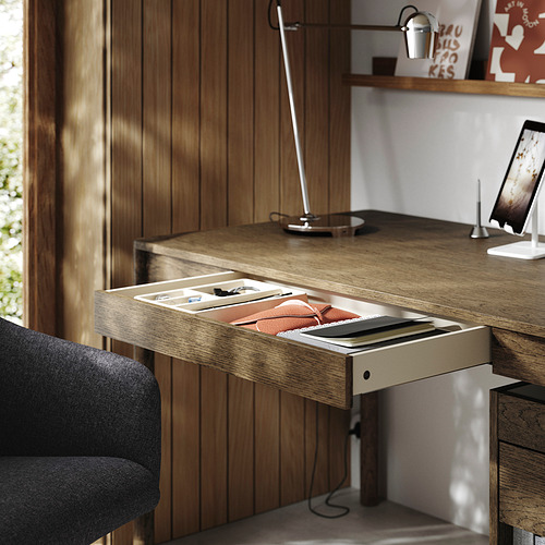 Escritorio de madera con cajón abierto, lámpara y soporte para tableta, que muestra la configuración organizada del espacio de trabajo.