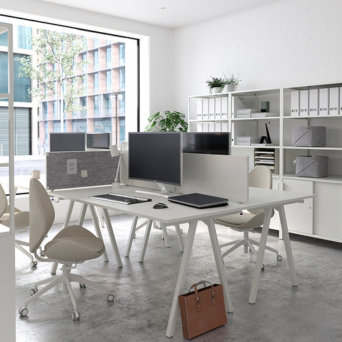 Moderno espacio de oficina con escritorios, sillas y unidades de almacenamiento trottén blancos. Ventana grande, luz natural, monitores de computadora y vista a la ciudad.