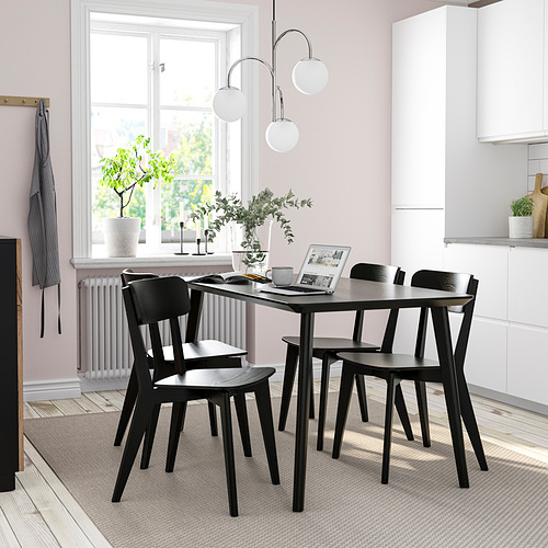 Juego de mesa y sillas de comedor LISABO negro, diseño moderno y minimalista, encaja perfectamente en espacios pequeños, suelos de madera clara y paredes rosas.