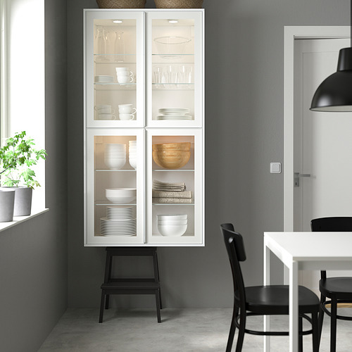 Vitrina HEJSTA con estructura metálica, platos organizados, junto a silla y mesa.