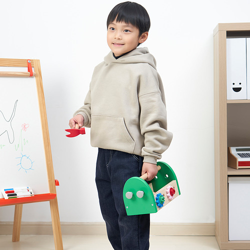 Niño sosteniendo un avión de juguete rojo y una caja de herramientas de juguete verde con accesorios coloridos, destinados a desarrollar habilidades motoras y creatividad.