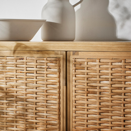 Mueble de ratán trenzado con estructura de madera natural. Detalles intrincados y pies ajustables. Jarrón y cuenco encima.