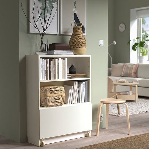Librería BILLY con ruedas con cestas. Taburete de madera y sofá en sala verde.