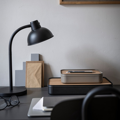 Configuración de escritorio negro con organizador HARVMATTA. Caja metálica con tapa de corcho entre lámpara y vasos.