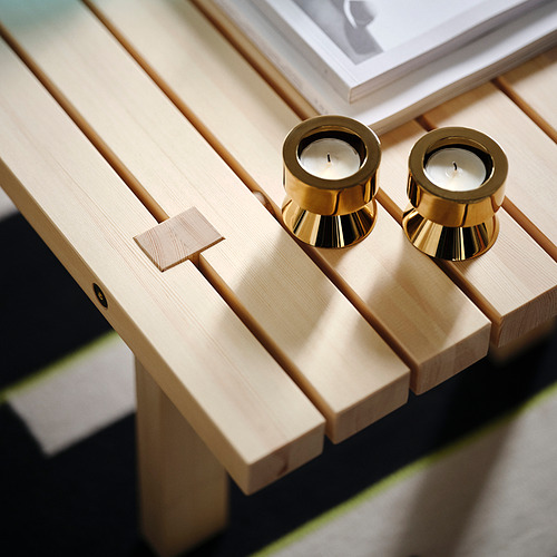Dos candelabros dorados de metal resistente sobre un amplio banco de madera, más grande que los libros.