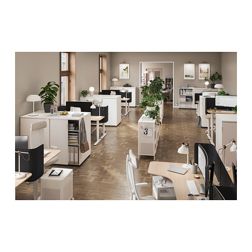 Moderno espacio de oficina con muebles y plantas blancas, con escritorios, sillas y unidades de almacenamiento con puertas corredizas.