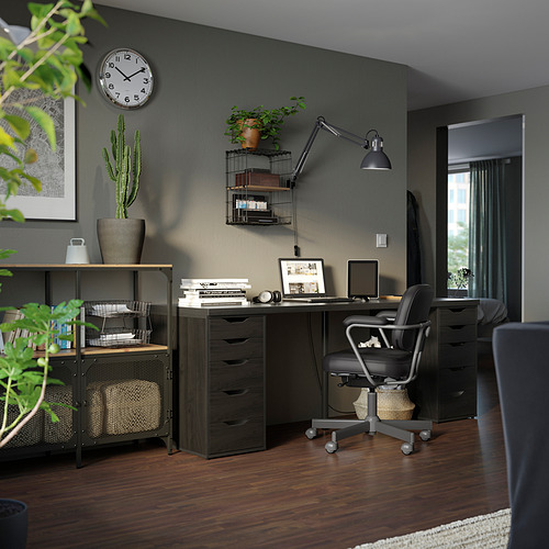 Escritorio LAGKAPTEN gris oscuro con cajones, ordenador, silla, estanterías, plantas y reloj de pared. Configuración de oficina en casa moderna y organizada.