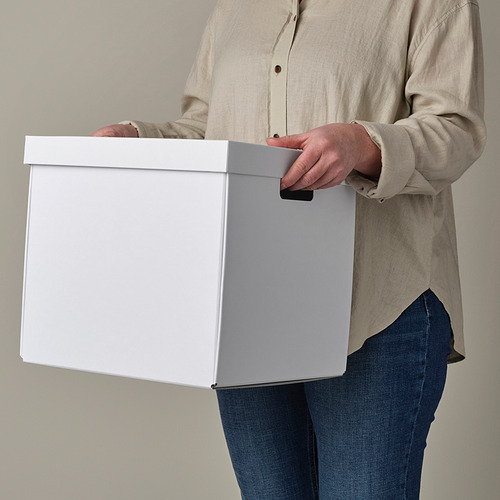 Persona que sostiene una caja de almacenamiento blanca con asas recortadas, ideal para estanterías kallax.