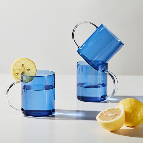 Dos tazas azules, una inclinada, con limón en una. Limones cerca, proyectando sombra. O, aún más corto: tazas azules con limón, sombras.