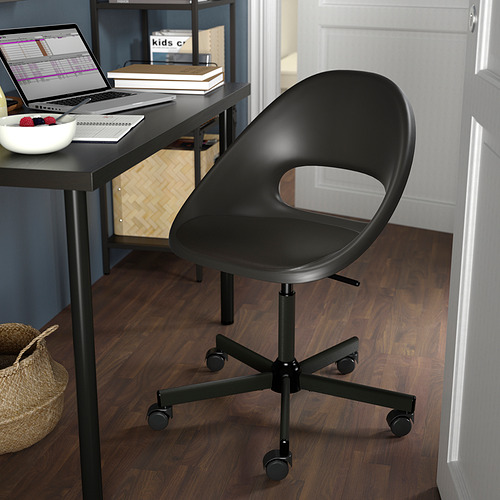 Silla de oficina negra con respaldo recortado, cinco ruedas, junto a un escritorio con computadora portátil, tazón y libros.