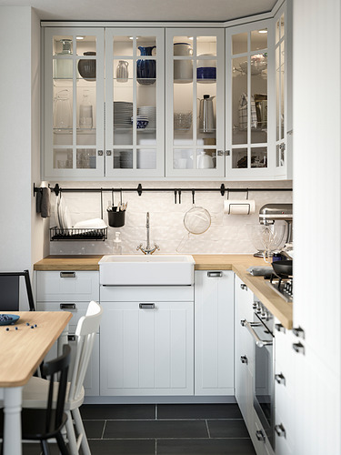 Cocina moderna con gabinetes blancos STENSUND, puertas de vidrio, encimeras de madera y electrodomésticos de acero inoxidable.
