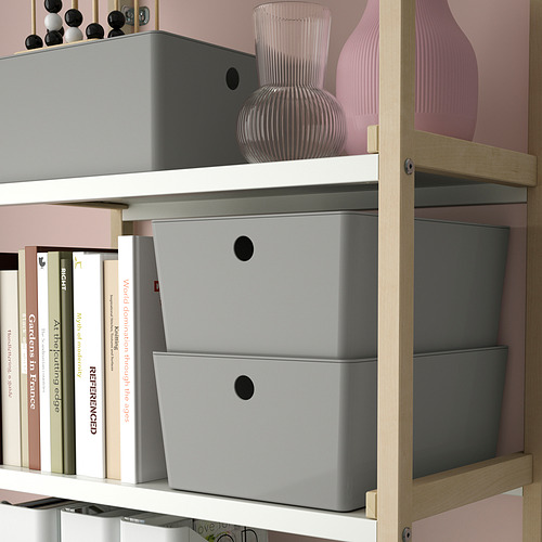 Estanterías de madera con cajas de almacenamiento grises y elementos decorativos. Las cajas se apilan y almacenan varios artículos domésticos, manteniendo el contenido libre de polvo.