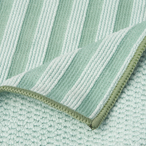 Primer plano de tela de microfibra suave, texturizada, de color verde claro y blanco a rayas con bordes de doble costura.