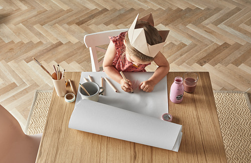 Dibujo infantil con papel MÅLA en mesa de madera.