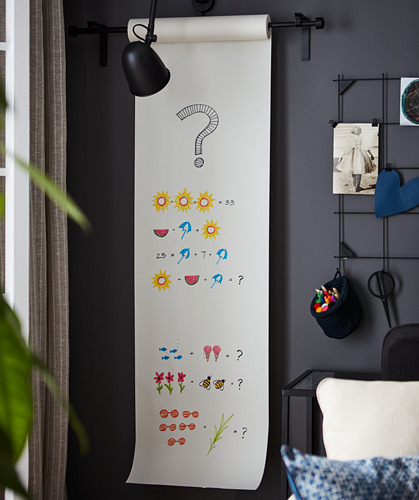 Papel de dibujo MÅLA montado en la pared con matemáticas coloridas; lámpara, silla, planta, insumos.
