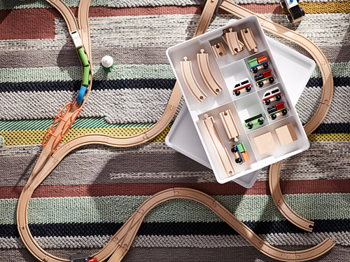 Vías de tren de madera, vehículos y almacenamiento. Juego de juguetes para niños con curvas y caja de almacenamiento. Huellas dispuestas sobre alfombra a rayas.