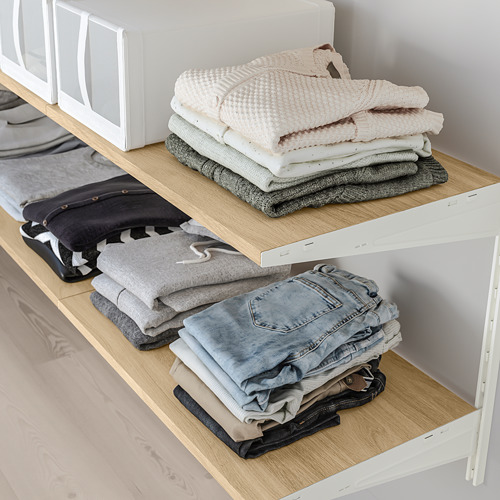 Ropa doblada cuidadosamente organizada en estantes de madera, lo que demuestra un almacenamiento eficiente y ordenado en el armario.
