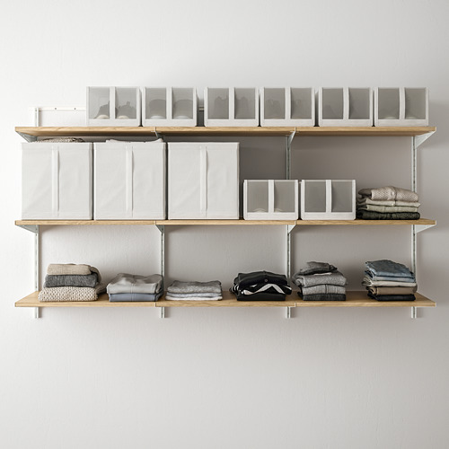 Estanterías modernas montadas en la pared con secciones plegables, que sostienen ropa ordenadamente apilada y cajas transparentes.