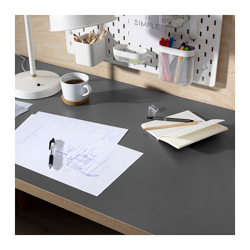 Montaje de escritorio con escritorio LAGKAPTEN gris, lámpara, café, boceto, cuaderno y bolígrafos.
