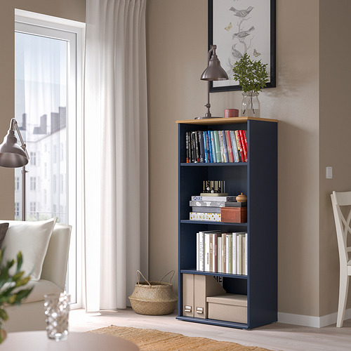 Estantería SKRUVBY azul con libros, decoraciones, silla blanca, cesta, cerca de la ventana.