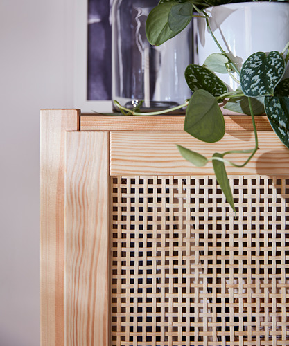 Un armario de madera IVAR, natural y marrón claro, con puertas de bambú trenzado que muestran plantas de interior.