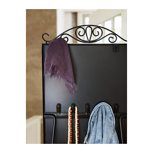 Un espejo negro con ganchos sostiene una bufanda morada, cuentas de colores y una chaqueta de mezclilla, lo que refleja una elegante configuración de organización.