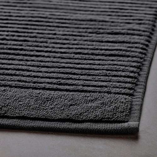 Primer plano de la alfombra de baño de rizo gris oscuro, que muestra su superficie texturizada y absorbente y su tejido resistente.