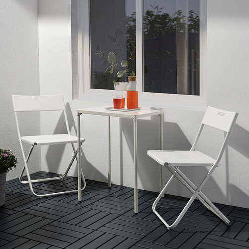 Pequeña mesa y sillas de exterior de metal blanco con tazas naranjas, perfectas para balcones.