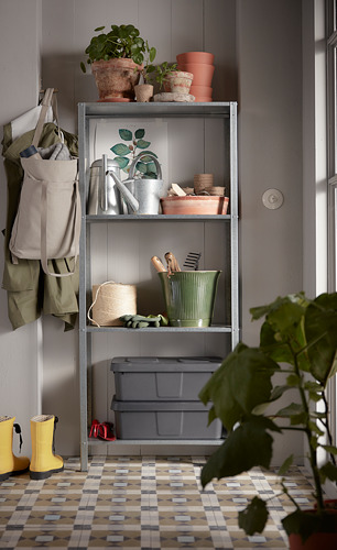 La estantería metálica almacena herramientas de jardinería, macetas y plantas. Gris, rectangular, organizado.