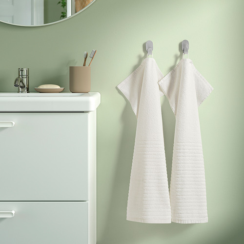 Baño de pared verde con toallas VÅGSJÖN, lavabo y espejo.
