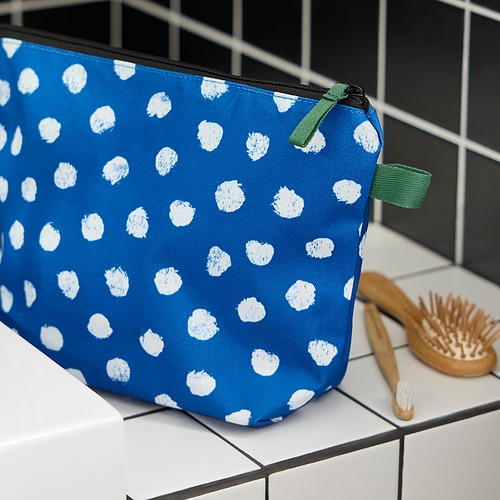 Bolso azul con puntos blancos, cremallera verde, pincel.