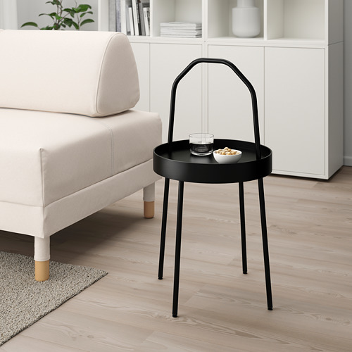 Mesa auxiliar redonda negra minimalista moderna cerca del sofá blanco, sostiene la bandeja y el tazón, tiene un práctico asa.