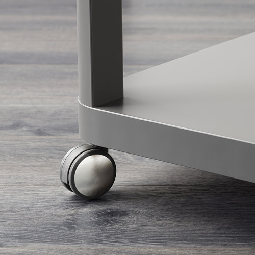 Primer plano de una moderna pata de mesa metálica con rueda giratoria lisa sobre suelo de madera.