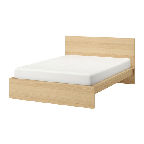 Una cama MALM en chapa de roble con colchón blanco, de diseño sencillo y moderno con cabecero alto.