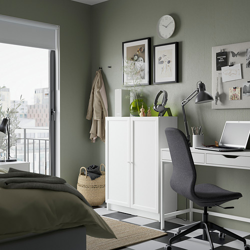 Oficina en casa bien organizada con estantería blanca BILLY, silla gris, lámpara de pie de madera y pared verde.