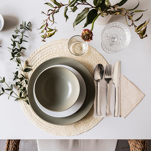 Mesa con cuenco verde, plato, cubiertos, vaso y servilleta de FÄRGKLAR verde sobre tapete texturizado. Decorado con vegetación.