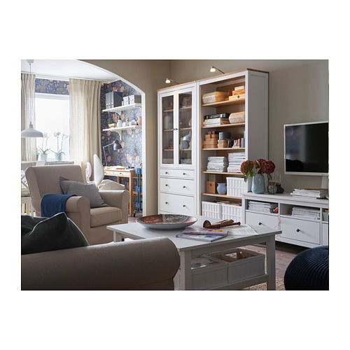 Sala de estar moderna con sofá beige, sillón gris, mueble blanco, mueble de TV y mesa de madera con elementos decorativos.