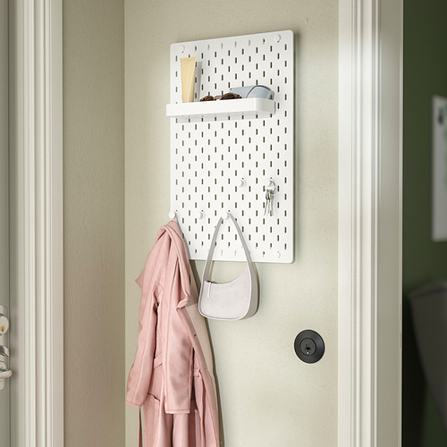 Organizador de tablero perforado SKÅDIS blanco con accesorios: estante, ganchos, abrigo, bolso y llaves.